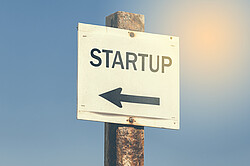 Ein Schild auf dem "Startup" steht, mit einem Pfeil, der nach links zeigt.