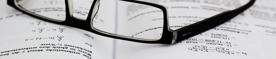 Brille liegt auf einem Buch mit mathematischen Formeln